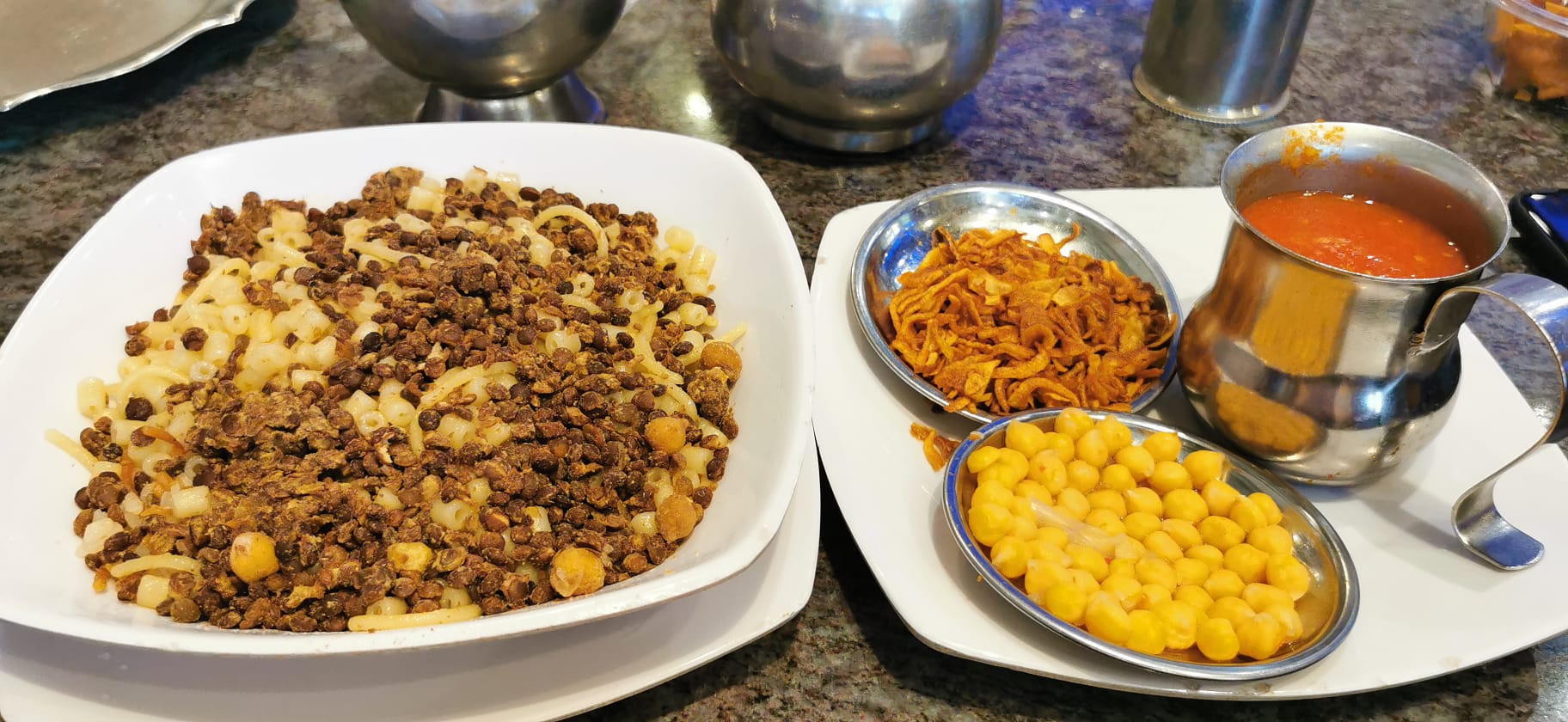 Piatto tipico egiziano con legumi, pasta, salsa e cipolla fritta
